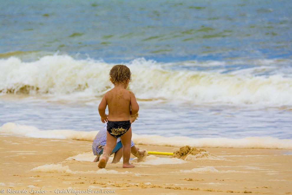 Imagem de duas criancas brincando na areia da Praia de Caraiva.